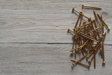 Yellow shiny screws laid out on wooden background