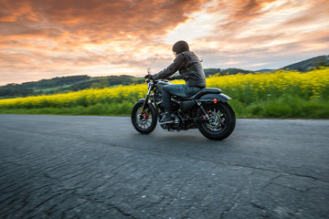 Man riding sportster motorcycle during sunset.