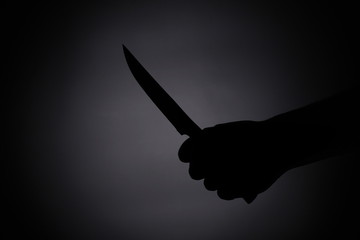 attacking with a knife / melee weapon shadow black silhouette in the dark