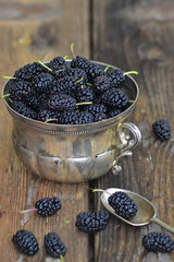 Fototapeta na wymiar Fresh blackberries in a silver bowl on rustic wooden background.