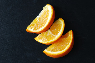 Slices of juicy orange on a black background.
