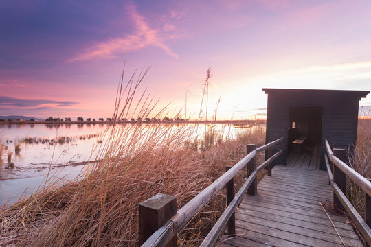 Holzsteg zu einer Beobachtungsh&uuml;tte f&uuml;r Vogelbeobachtung im Ebro Delta nahe Barcelona am Morgen zu Sonnenaufgang