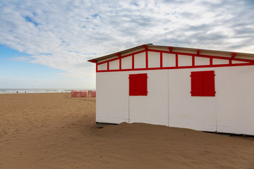 Red beautiful terrace on the beach. A building for shelter from the sun against the background of sand.