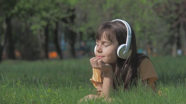 The child in the headphones is listening to music. The girl enjoys music in nature.