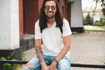 Portrait attractive man with sunglasses on urban background smil