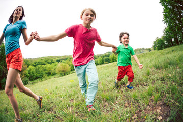 A woman with children runs along the grass.