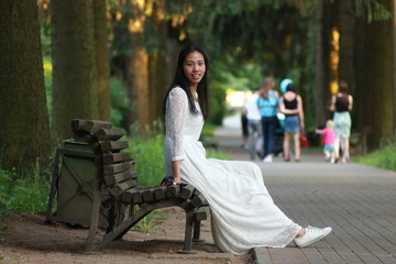 Красивая китайская девушка на скамейке в парке