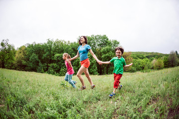 A woman with children runs along the grass.