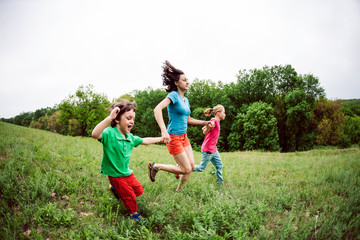 Obraz premium A woman with children runs along the grass.