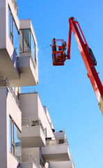 Man cleaning facade of a modern minimalistic apartment building on a telescopic boom lift using...