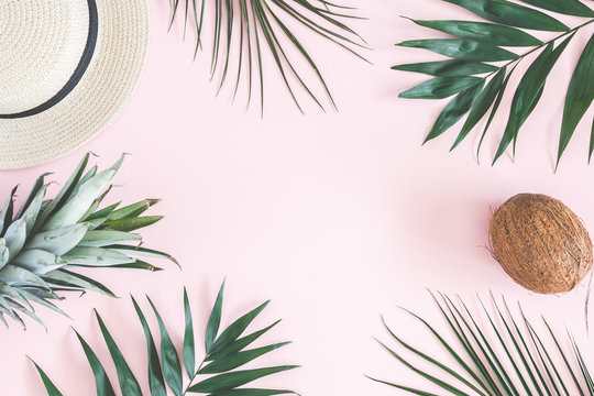 Summer composition. Tropical palm leaves, hat, pineapple, coconut on pastel pink background. Summer concept. Flat lay, top view, copy space
