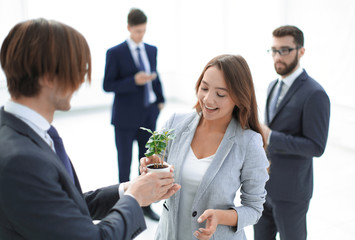 businessman and businesswoman holding a pot with sprouts