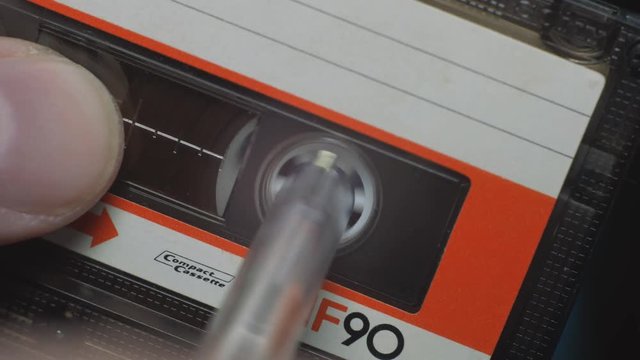 Hands of a man rewinding a compact cassette