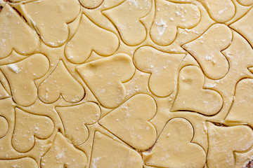 Preparation of the dough, roll out with a rolling pin and cut shapes in the form of hearts. Baking cookies for the holiday. Close-up.
