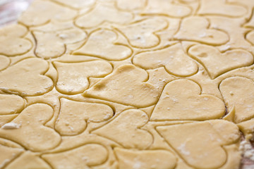 Preparation of the dough, roll out with a rolling pin and cut shapes in the form of hearts. Baking cookies for the holiday. Close-up.