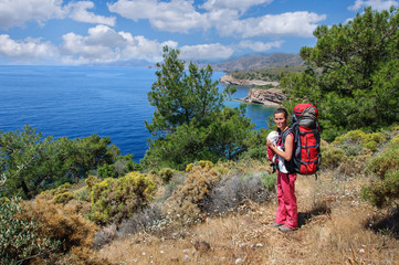 A woman with a baby in a sling and a large backpack travels along the Carian path. Turkey