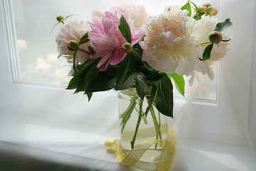A bouquet of white and pink peonies in a glass vase