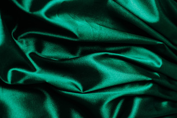 Green fabric in the folds. drapery. shine on silk. Sewing