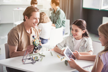 Portrait of happy male and glad children playing with toy while using electronic tablet