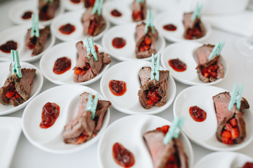 a sumptuous appetizer of ham rolls on white plates.