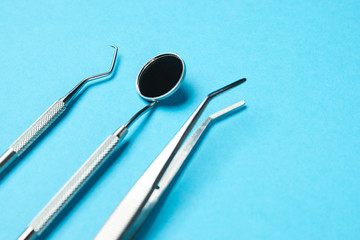 Professional Dentist tools on blue background with copy space. Dentist mirror, forceps curved,...