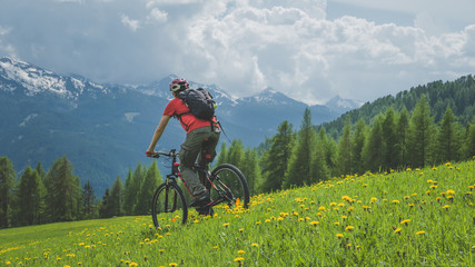 MTB bicycle ride in the mountain meadow, rear view of cyclist in