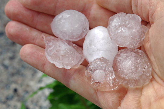 Gro&szlig;e Hagelk&ouml;rner in der Hand von einer Frau