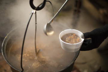 A person pouring some soup in a cup.