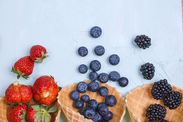 Different berries and fruits on a blue background. Free space for text. Copy space. Flat lay.