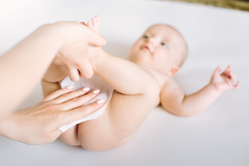 Newborn baby getting a diaper change: mom wiping baby's bottom with baby wipe