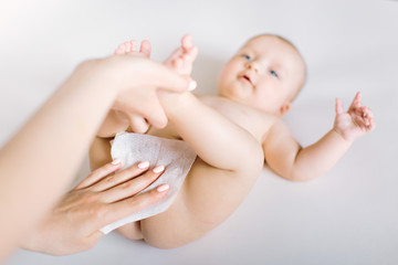 Newborn baby getting a diaper change: mom wiping baby's bottom with baby wipe