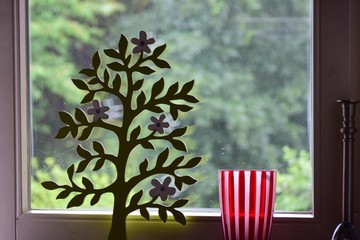 Vase und Schmuckbaum vor einem Fenster