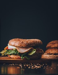 Dark bagel ham sandwich on cutting board
