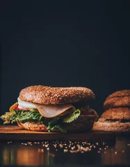 Draagtas Dark bagel ham sandwich on cutting board © Jessica