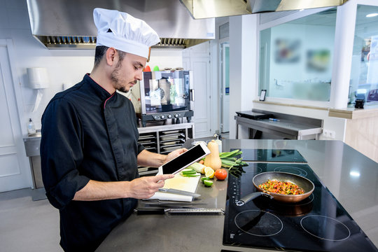 young chef by referring to a Smartphone or tablet in a professional kitchen