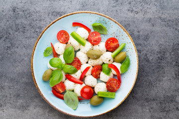 Delicious caprese salad with ripe cherry tomatoes and mini mozzarella cheese balls with fresh basil leaves.