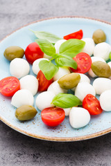 Delicious caprese salad with ripe cherry tomatoes and mini mozzarella cheese balls with fresh basil leaves.