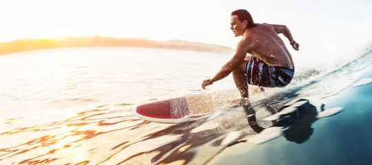 Surfer rides the glassy speedy wave in tropics at sunrise. Costa Rica - obrazy, fototapety, plakaty