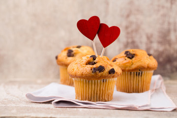 Homemade chocolate muffins with heart, vintage background.