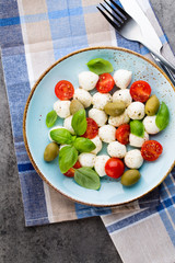 Delicious caprese salad with ripe cherry tomatoes and mini mozzarella cheese balls with fresh basil leaves.