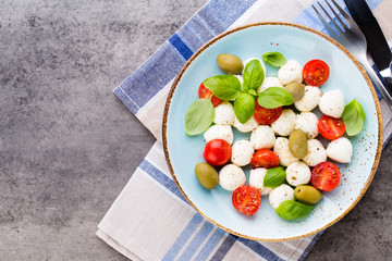 Delicious caprese salad with ripe cherry tomatoes and mini mozzarella cheese balls with fresh basil leaves.