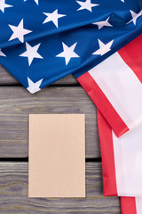 American flag and blank paper sheet. Folded flag of USA and empty envelope on wooden background, top view.