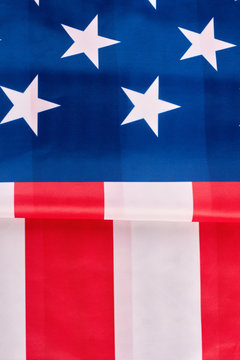 USA national flag background. Close up folded satin flag of United States of America, vertical image. Stars and stripes flag. Idea for banner. Happy fourth of July.
