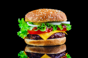 Big tasty hamburger or cheeseburger on black background with grilled meat, cheese, tomato, bacon,...