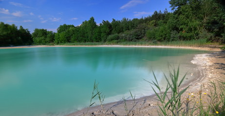 Jezioro z piękną lazurową (szmaragdową) wodą, otoczone przez piaszczystą wąską plażę i gęstą, bujną zieleń, dookoła, czyste, błękutne niebo, nikogo, atmosfera spokoju