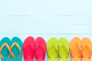 Beach accessories including colorful flip flop on bright blue pastel wooden background for summer holiday and vacation concept.