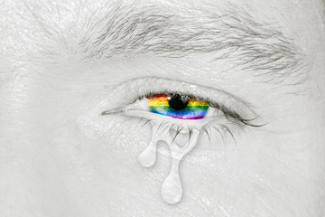 Crying eye with rainbow flag iris on black and white face. Concept of sadness and pain for the homosexual discrimination. Flag symbol of pride and freedom LGBT.