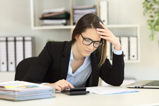 Worried bookkeeper calculating expenses at office