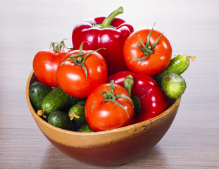 on a table in wooden plate cucumbers, tomatoes and pepper