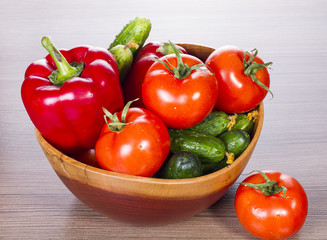on a table in wooden plate cucumbers, tomatoes and pepper
